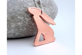 bronze hare necklace leaning against a stone